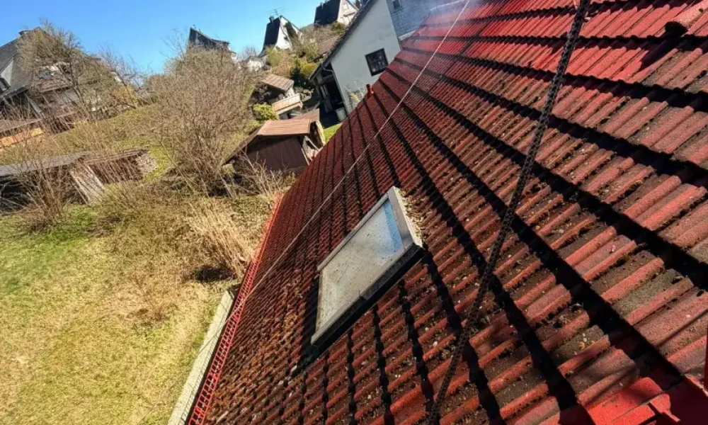 Dachreinigung eines roten Ziegeldachs während des Arbeitsprozesses